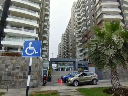 a blue disabled sign in a parking lot with a palm tree at Departamento con Vista al Mar in Lima