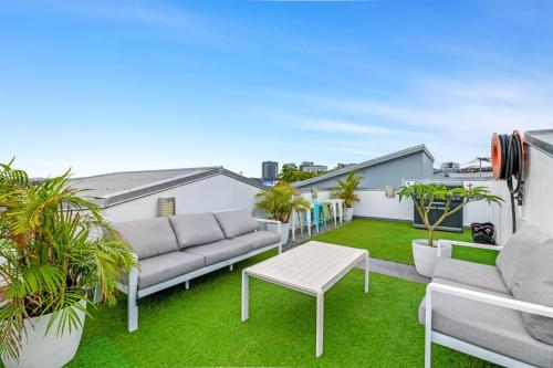 an apartment patio with a couch and a table at Spacious 2-Bed with Private Rooftop & BBQ Access in Brisbane