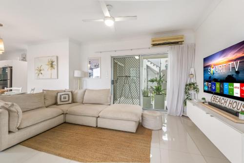a living room with a couch and a tv at Spacious 2-Bed with Private Rooftop & BBQ Access in Brisbane
