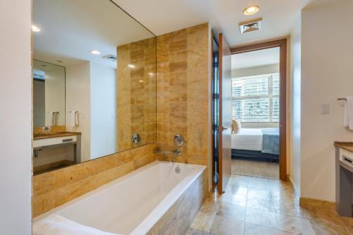 Un baño con bañera grande y un dormitorio. en Brickell 32th Floor AKA by Palermo Home Miami, en Miami