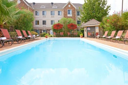 a large swimming pool with chairs and a building at Staybridge Suites Irving Las Colinas by IHG in Irving