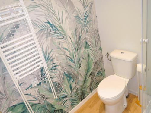 een badkamer met een toilet en tropisch behang bij Holiday homes with swimming pool, close to the sea in Wapnica