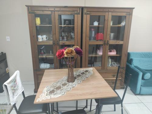 een houten tafel met een vaas met bloemen erop bij Apartamento Ótima Localização Turismo Faculdade in Bento Gonçalves