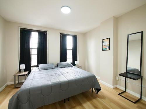 a bedroom with a large bed and two windows at Cozy 1BR Getaway with Wifi - Mins to NYC in Paterson