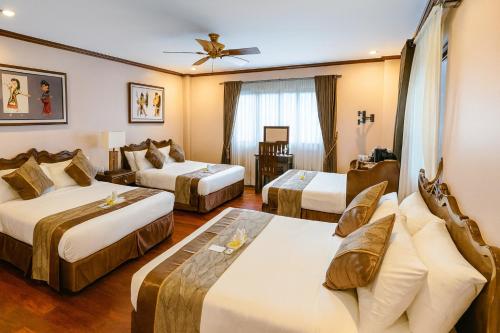 a hotel room with three beds and a couch at Leonard Wood Pines Hotel in Baguio