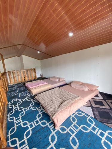 two beds in a room with a wooden ceiling at Lavenda homestay syari'ah in Dieng