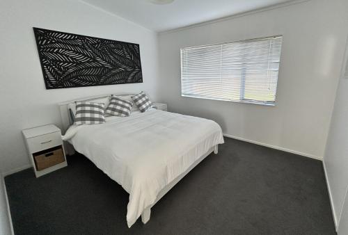 a white bedroom with a bed and a window at The Shores Lakefront Retreat in Omamari