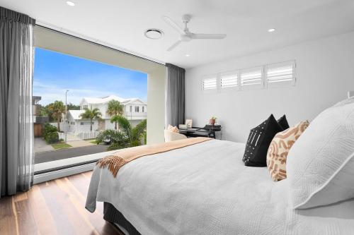 Nalu Beach House - Kingscliff Getaway by uHoliday في كينغسكليف: غرفة نوم بسرير كبير ونافذة كبيرة