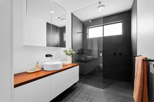 Nalu Beach House - Kingscliff Getaway by uHoliday في كينغسكليف: حمام أبيض مع حوض ودش