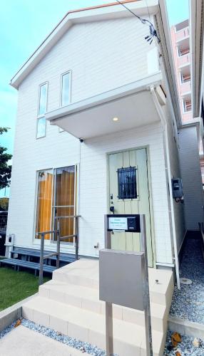 a white house with a sign in front of it at Chatan Beachside House in Chatan
