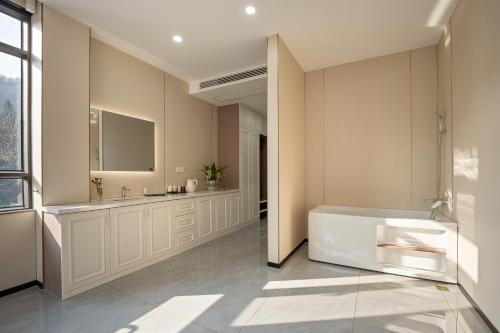 een badkamer met een wit bad en een wastafel bij 花筑庐江满山红遍民宿 