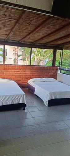 two beds in a room with a brick wall at Villa Campestre Eagle in Girardot