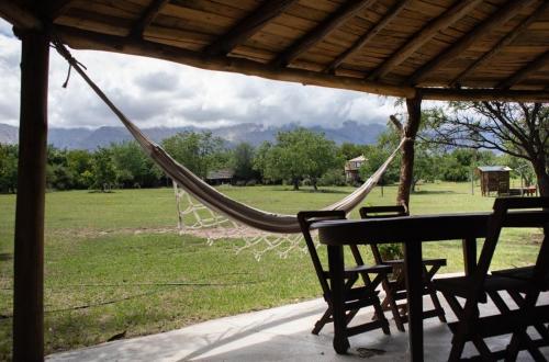 un hamac sur un porche avec une table et des chaises dans l'établissement Cabañas Bendita Tierra- Crespin, à Los Molles