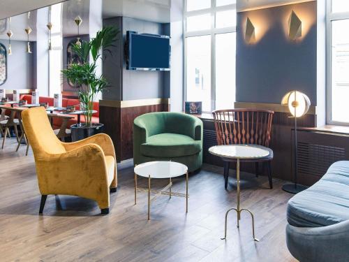 a waiting room with chairs and a couch and tables at Mercure Nancy Centre Place Stanislas in Nancy