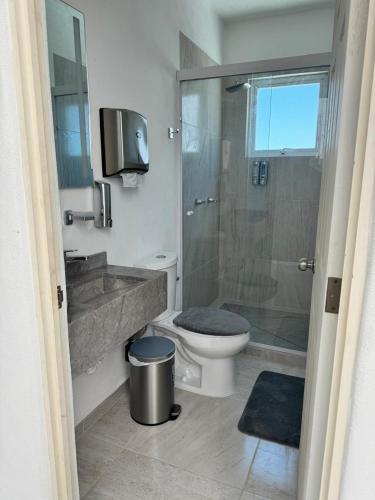 a bathroom with a toilet and a shower and a television at Villa Yolanda in Acapulco