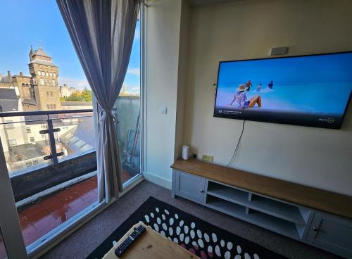 a living room with a flat screen tv and a large window at Cardiff City Apartment near Principality Stadium, Cardiff Arms Park & Cardiff Castle in Cardiff
