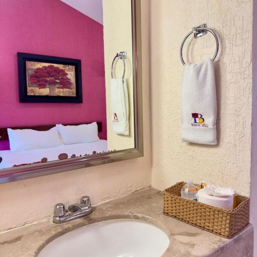 a bathroom with a sink and a mirror and a bed at Hotel Barranquilla in Campeche