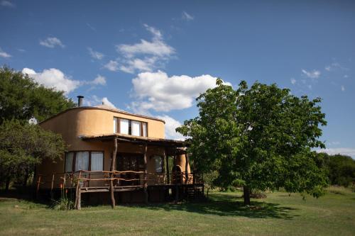 une maison dans un champ avec un arbre dans l'établissement Cabañas Bendita Tierra - Calandrias, à Los Molles