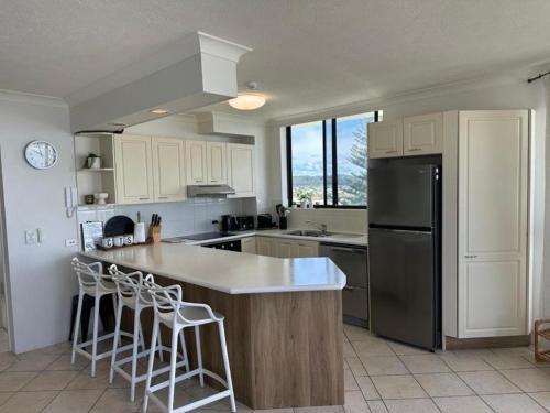 a kitchen with white cabinets and a black refrigerator at Seascape Serenity in Palm Beach in Gold Coast