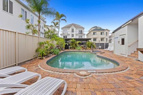 a swimming pool in a yard with white chairs at Seascape Serenity in Palm Beach in Gold Coast