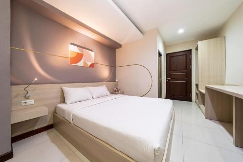 a small bedroom with a bed and a desk at Cove Ananya in Surabaya