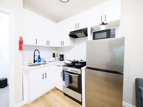 a kitchen with white cabinets and a stainless steel refrigerator at Comfy 1-Bedroom Escape Close to NYC with Wifi in Paterson