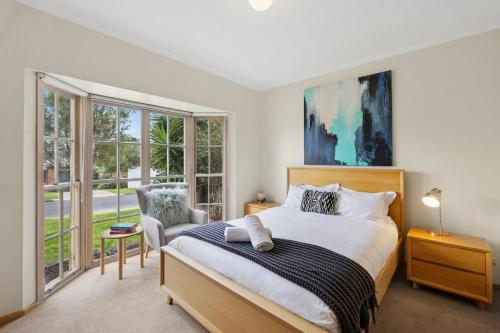 una camera da letto con un letto, una sedia e finestre di Riviera Retreat, Coastal Comfort Near Jan Juc Surf Beach a Bellbrae