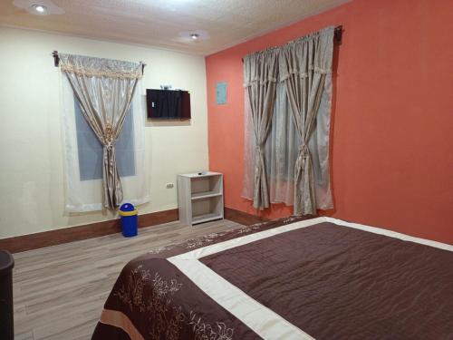 a bedroom with orange walls and a bed and windows at Casa Cifuentes in La Esperanza