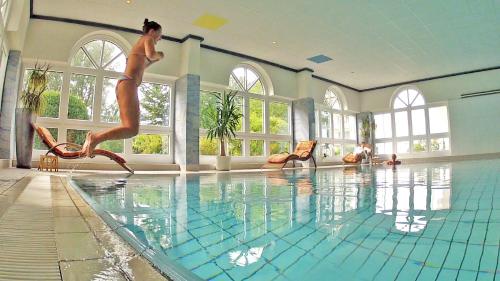 Uma mulher está a saltar para uma piscina. em Hotel Sonnengarten em Bad Wörishofen