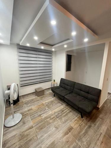 ein Wohnzimmer mit einem schwarzen Sofa und einem Ventilator in der Unterkunft Apartamento moderno en Ibagué in Ibagué