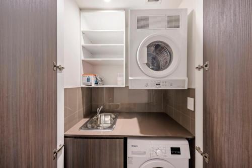 een keuken met een spoelbak en een wasmachine bij Stylish 2BR Next to Parramatta Station with Pool in Sydney