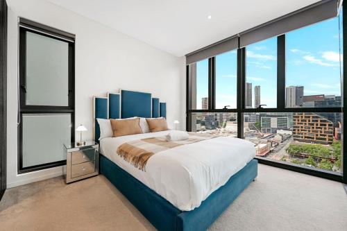 een slaapkamer met een groot bed en grote ramen bij Stylish 2BR Next to Parramatta Station with Pool in Sydney
