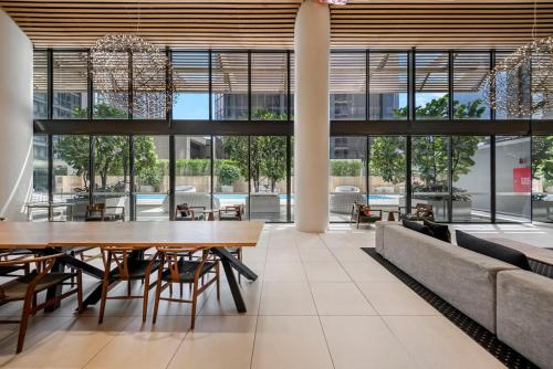 a dining room with tables and chairs and large windows at Stylish 2BR Next to Parramatta Station with Pool in Sydney