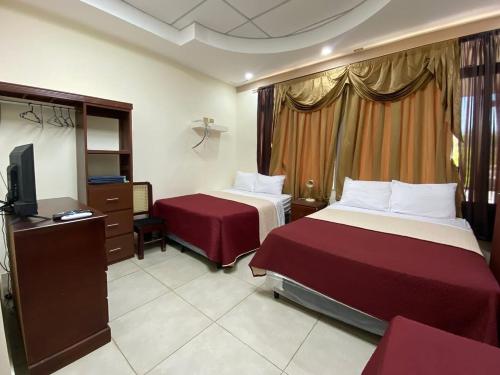 ein Hotelzimmer mit zwei Betten und einem Fernseher in der Unterkunft Hotel D' Palacio Real in San Miguel