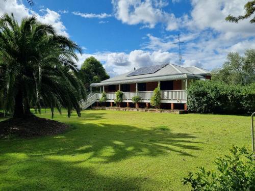a house with a palm tree in front of a yard at Maranda Country Estate 5 Bedrooms with Pool, Spa & EV in Broke