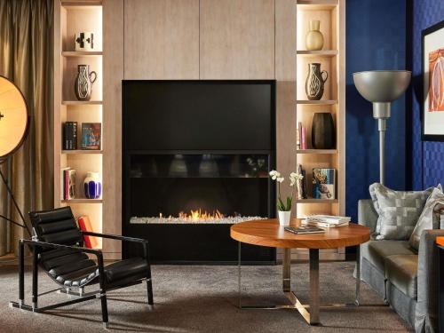 a living room with a fireplace and a table at Sofitel Paris Arc De Triomphe in Paris