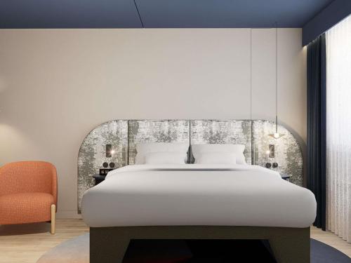 een slaapkamer met een groot wit bed en een oranje stoel bij Mercure Hotel Den Haag Central in Den Haag