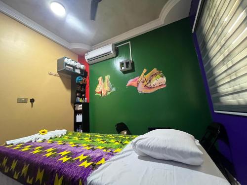 ein Schlafzimmer mit einem Bett und einer grünen Wand in der Unterkunft Dubai Dollar Beach Resorts in Tema