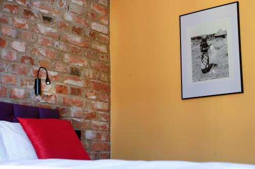 a bedroom with a brick wall and a bed with a red pillow at Hellstens Glashus in Stockholm