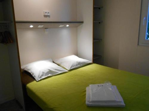 a bedroom with a green bed with white pillows at Mobil home avec terrasse à Gurmençon - API-1-52-612 in Gurmençon