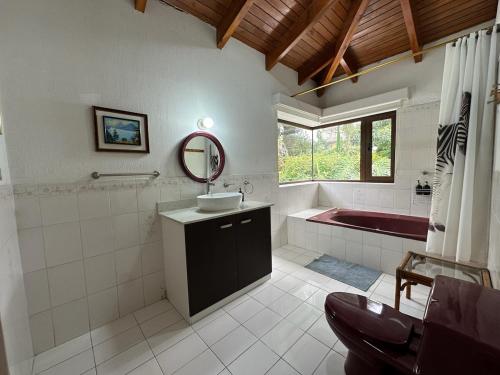 Un baño con lavabo, bañera y espejo. en Casa Belen Panajachel, en Panajachel