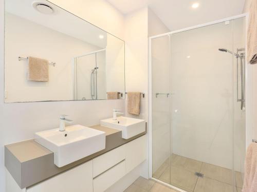 een witte badkamer met twee wastafels en een douche bij Foreshore Bradman in Diddillibah