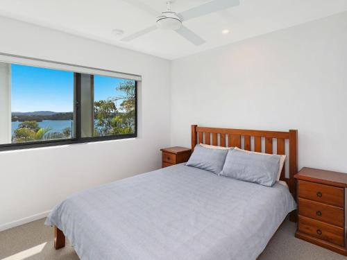 een slaapkamer met een bed en twee ramen bij Foreshore Bradman in Diddillibah