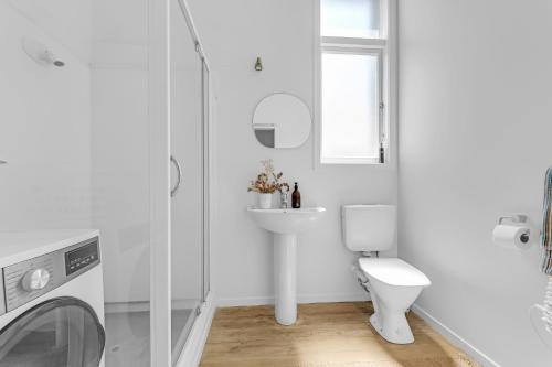 um banheiro branco com vaso sanitário e pia em Bespoke Stays - Rustic Stanley Bay Apartment em Auckland