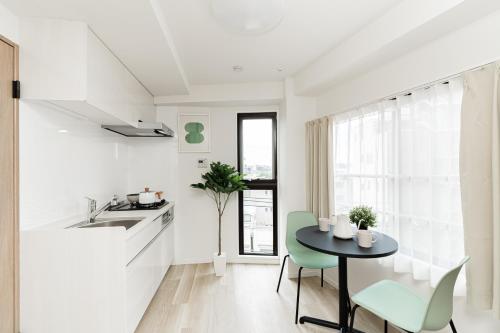 a white kitchen with a black table and green chairs at Sunlit Canopy - A Cozy Stay in Tokyo Shinjuku Area, with Easy City Access to Shibuya in Tokyo