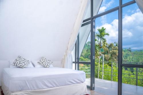 a bedroom with a bed and a large window at Sinharaja River Lodge in Nikawatawana