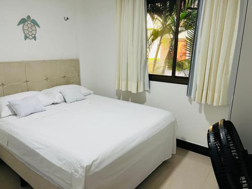 un letto bianco in una stanza con una finestra di Manhattan Beach Riviera 2 Terreo ad Aquiraz