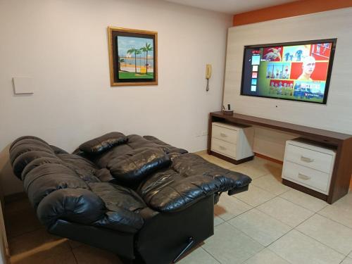 a living room with a leather couch and a flat screen tv at Villa Anto in Encarnación