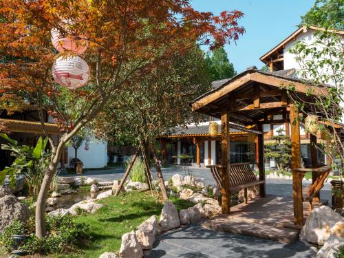een paviljoen in een tuin voor een gebouw bij Chengdu Xiaoya Yard Hot Spring Hotel,Enjoy Soaking in natural hot springs,Traditional Chinese afternoon tea,Exquisite fruit platter in Longqiao