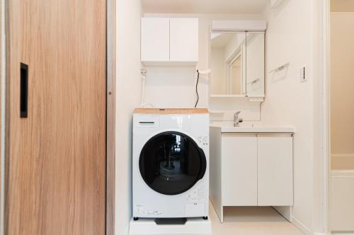 a washing machine in a kitchen next to a sink at Sunlit Canopy - A Cozy Stay in Tokyo Shinjuku Area, with Easy City Access to Shibuya in Tokyo